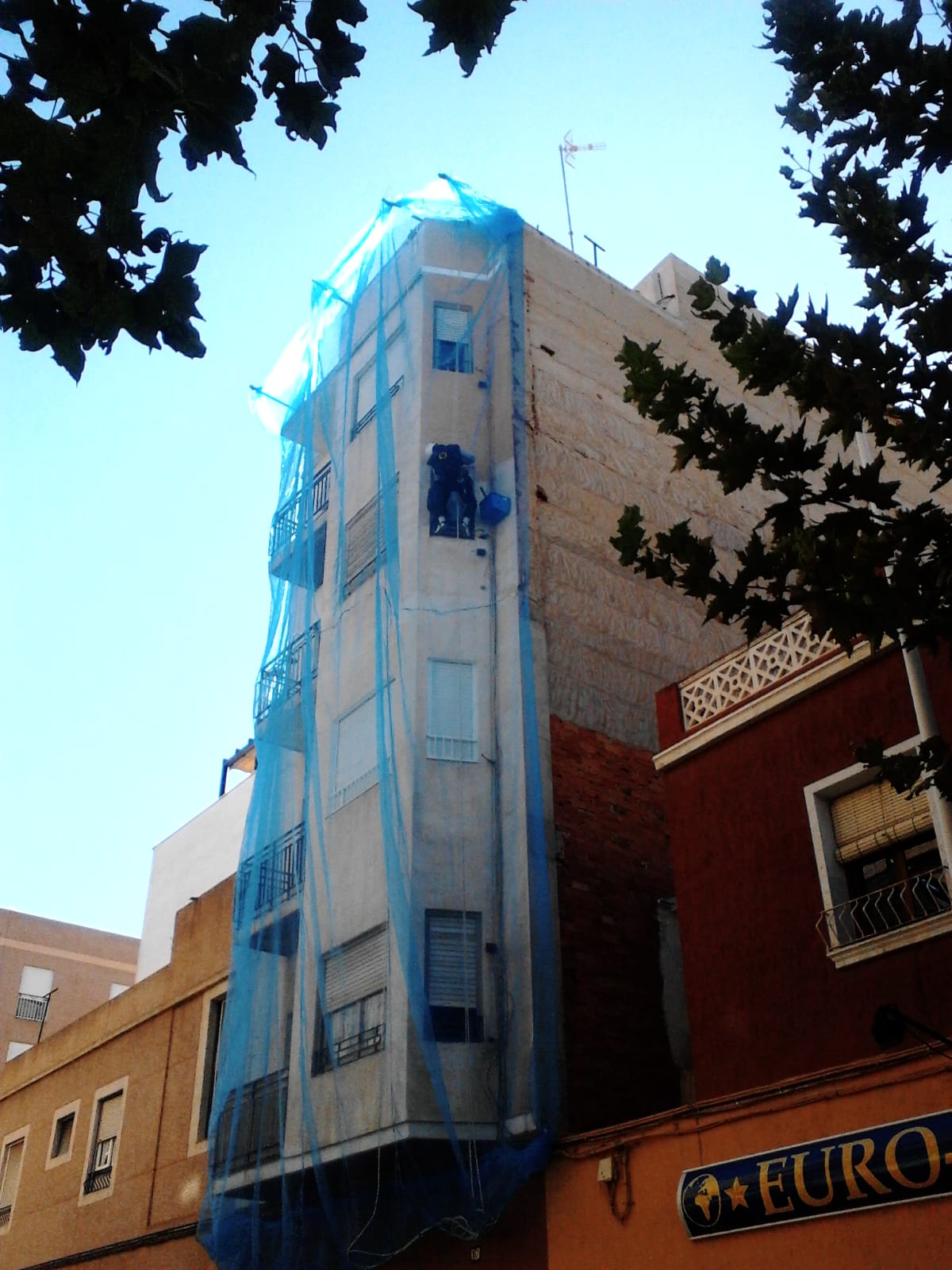 Técnico aplicando tratamiento en fachada con cuerdas certificadas